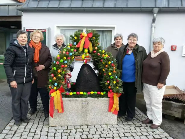 Damen schmücken Osterbrunnen